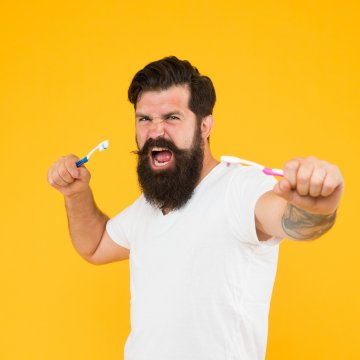 Man with a toothbrush in both hands against a yellow background